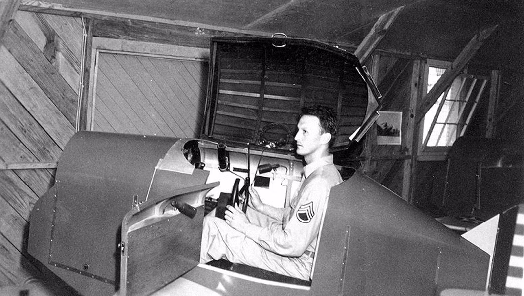 Link Trainer with a U.S. military pilot sitting inside the simulator.